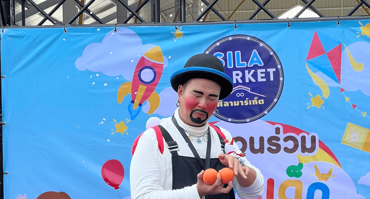 ผู้ชายแต่งตัวเป็นตัวตลกอยู่บนเวทีกำลังเล่นมายากล