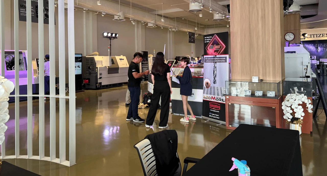 บูธเปิดตัวสินค้าสีดำขนาดใหญ่ มีผู้เข้าร่วมงานผู้ชายและผู้หญิงกำลังดูสินค้า