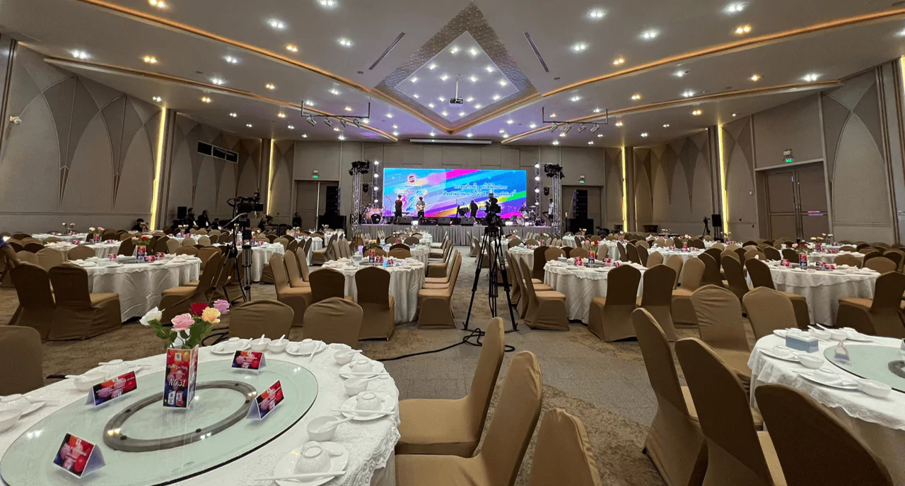 ภาพบบรยากาศห้องจัดเลี้ยงมีโต๊ะกลมสำหรับทาอาหารมีเวทีการแสดงอยู่ด้านหน้า