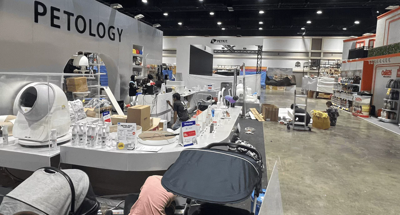 ด้านข้างบูธขายสินค้า พนักงานกำลังติดตั้งบูธขายสินค้าเกี่ยวกับสัตว์เลี้ยงขนาดใหญ่ และมีที่เข้าห้องน้ำสัตว์เลี้ยงอัตโนมัติ