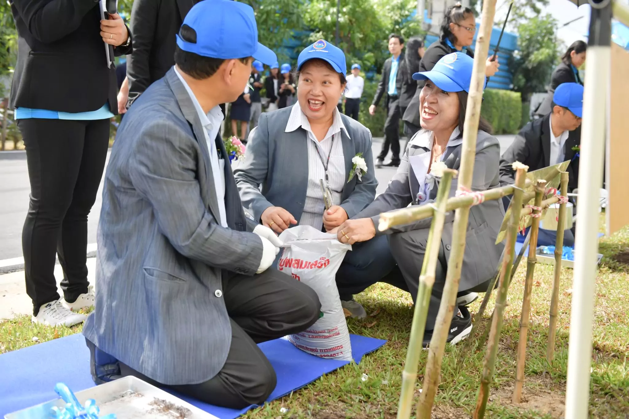 ผุ้ชายและผู้หญิงใส่สูสีเทากำลังจับถุงปุ๋ย